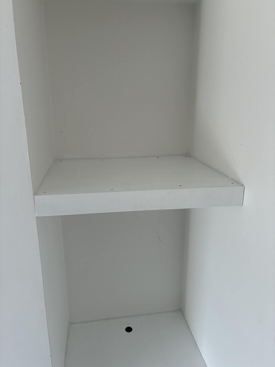Custom-built white shelving fitted into an alcove